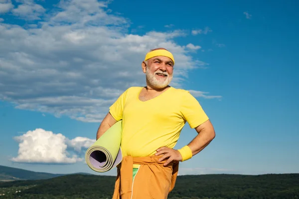 Happy active old man holding exercise mat. Healthy lifestyle concept. Sport. Freedom retirement concept. Cheerful aged men holding yoga mats.