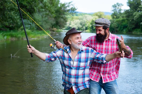年轻人和老成熟的人飞钓鱼。男子钓鱼和放松，同时享受爱好。钓鱼。快乐的祖父和孙子与钓鱼竿在河泊位. — 图库照片