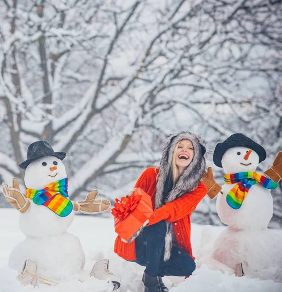 Roliga snögubbar. God jul och Happy Holidays. Christmas förberedelse-rolig tjej gör snögubbe. Snögubbe och rolig flicka i snön. — Stockfoto