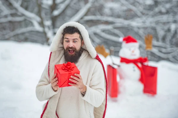 Kellemes karácsonyi ünnepeket és boldog új évet. Örömteli apa tartsa ajándék és szórakozás a hóember a Winter Park. Holly Jolly szajré karácsonyi és Noel. — Stock Fotó