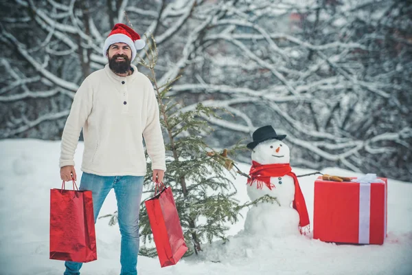 Happy father with Christmas gift over winter snowman background. Winter emotion. Handsome Santa Claus. Christmas winter people portrait.