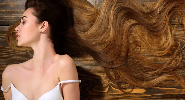 Žena s krásnými dlouhými vlasy na dřevěném pozadí. Dlouhé vlasy. Účes módy. Dlouhé zdravé vlasy. — Stock fotografie