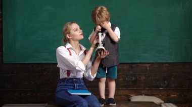 Kadın öğretmen biyolog yeşil tahta arka plan üzerinde okulda mikroskop kullanmak için çocuk öğretir. Okula geri dön. Eğitim, okul, çocuk kavramı. İlginç biyoloji. Araştırma. Dünyayı keşfetmek.