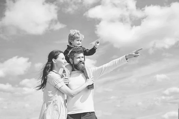 Papa, Mama und der kleine Sohn. Glückliche Familie - Sohn spielt mit Papierflugzeug. Porträt eines glücklichen Vaters, der seinem Sohn Huckepack auf den Schultern gibt, seine Frau umarmt und nach oben blickt. — Stockfoto
