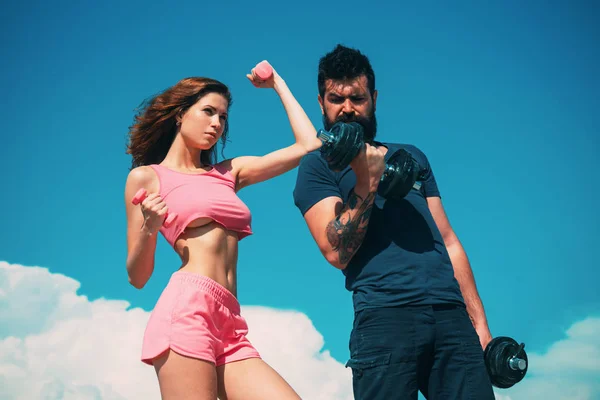 Fit and strong. Sensual fit woman and bearded man doing sport exercises. Athletic woman and strong hipster keeping bodies fit with dumbbell workout. Sexy couple of athletes feeling fit and healthy