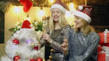 Happy Girls yeni yıl veya Noel tatili karşılamak. Arkadaşlar kırmızı Santas şapka ve şampanya ile Noel veya Yılbaşı partisi kutluyor. Mutlu Noeller ve Mutlu Yıllar. Yeni Yıl arka plan.
