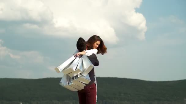 Koncept módy, nakupování, štěstí a módních blogů. Muž v dlaních víjí dívku s mnoha balíky na nebesích. Muž, který nakupuje ženu. Šťastný mladý pár. — Stock video