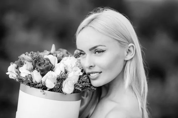 Spring woman with present flowers. Womens day. Beauty day in spring. Flowers box for woman. Valentine Beauty blonde girl. Joyful model having fun celebrating with colorful flowers.