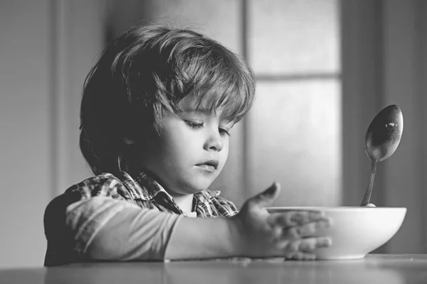 Kid jongen eten gezond eten thuis. Goedemorgen in gelukkige familie. Kleine jongen zittend aan de tafel en het eten van melk snack. — Stockfoto