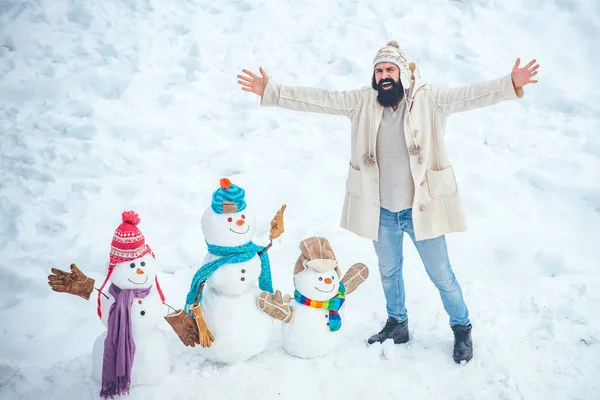 Feliz Navidad y Felices Fiestas. Preparación de Navidad - hombre barbudo divertido hacer muñeco de nieve. Muñeco de nieve y hombre barbudo divertido en la nieve . — Foto de Stock