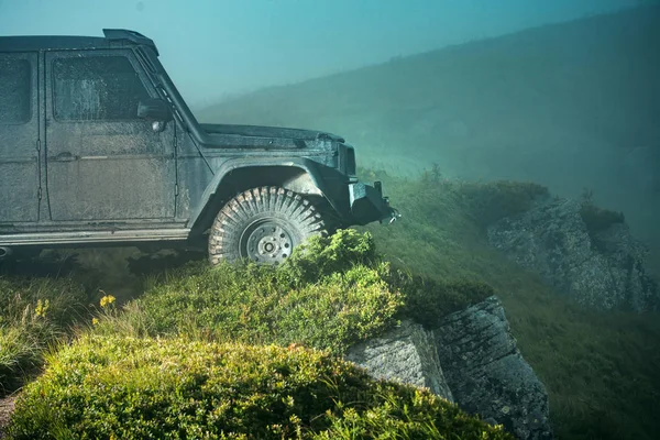 Ein klassischer Geländewagen überquert Wasser mit Spritzern auf schlammiger Straße. Extreme Offroad-Tour im Wald. Offroad-Auto auf schlechter Straße. — Stockfoto