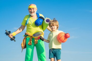 Çocuklar için spor. Baba ve oğul spor yapıyor. Ailecek vakit geçiriyoruz. Kıdemli bir adam ve küçük tatlı bir çocuk mavi gökyüzü arka planında egzersiz yapıyorlar - izole edilmiş.