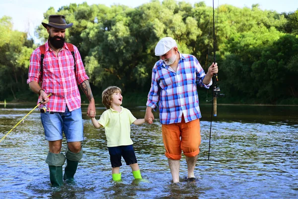 Dad and son fishing at lake. Young - adult concept. Men hobby. Grandfather, father and boy fishing together.