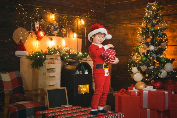 Boy cute child cheerful mood play near christmas tree. Merry and bright christmas. Lovely baby enjoy christmas. Santa boy little child celebrate christmas at home. Childhood memories. Family holiday