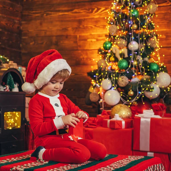 Маленький мальчик Санта празднует Рождество дома. Семейный праздник. Мальчик милый ребенок веселый настроение играть возле рождественской елки. Счастливого и светлого Рождества. Прекрасный ребенок наслаждается Рождеством. Детские воспоминания — стоковое фото