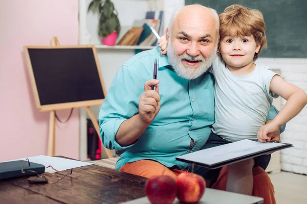 Rozkošný malý kluk s dědečkem ve třídě. Portrét dědečka a vnuka na tabuli v učebně. — Stock fotografie