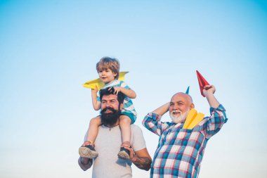 Mutlu erkek ailesi birlikte eğlenir. Çocukluk kavramı. Boş zaman aktivitesi. Oğlu baba ve büyükbaba mavi yaz gökyüzünde oynuyor. Babalar günü kavramı.
