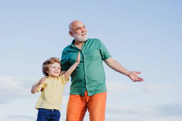 Два поколения - выходные вместе. Два разных поколения: дедушка и внук вместе. День Отцов. Счастливые отец и сын на лугу летом . — стоковое фото