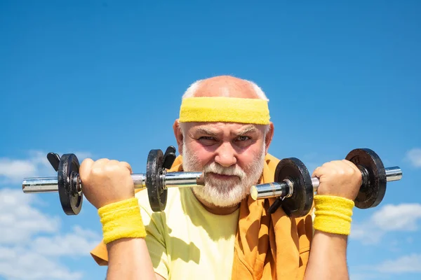 Férias de verão e ativas. Como o desporto. Esportista sénior a levantar halteres. Homem idoso treino . — Fotografia de Stock