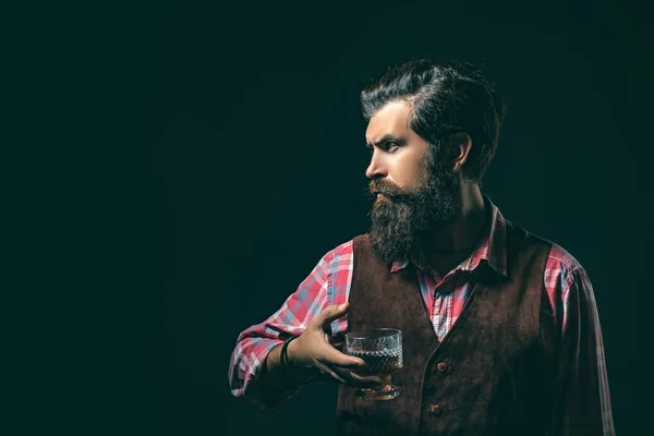 O homem com barba tem conhaque de vidro. Homem barbudo elegante elegante Bartender detém copo de uísque. Sommelier homem . — Fotografia de Stock