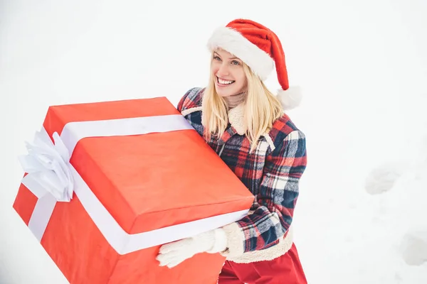 Santa femme tient une grande boîte cadeau avec de l'espace de copie pour votre texte. Fille de Noël tenant un grand cadeau. Grande boîte cadeau. Fille de Noël fou pousse un gros cadeau sur fond d'hiver de neige. — Photo