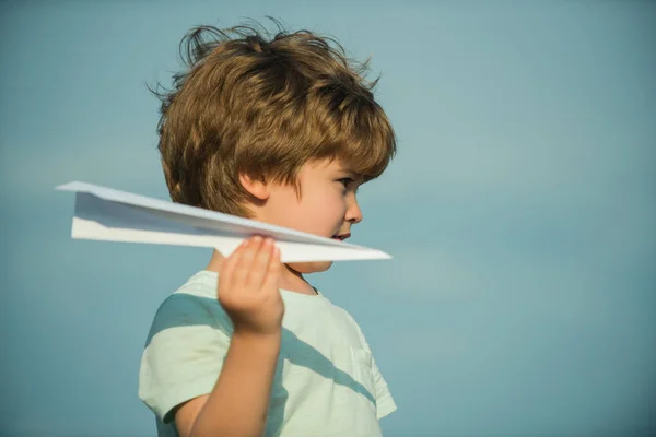 Feliz niña. Niño lindo en el prado con un avión de papel de juguete en el verano en el fondo del cielo. Viajes familiares y concepto de vacaciones . — Foto de Stock