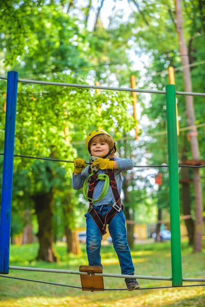 Kind jongen plezier in Adventure Park. Gelukkig kind klimmen in de bomen. Schattig kind jongen. Portret van een mooi kind op een touw park tussen de bomen. Kind. — Stockfoto