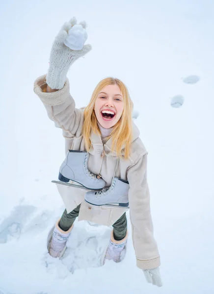 Lustig lächelnde junge Frau im winterlichen Freien. Mit lustigem Hut, kariertem Schal und Mantel. Frohe Frau im Winterspaß. Winterspiel. Schöne lächelnde junge Frau in warmer Kleidung mit Schlittschuhen. — Stockfoto