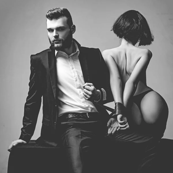 Burlarse y seducir. Chica sexy nalgas desnudas. Amantes apasionados. Dominación sexual. Sumisión sexual. Macho bien arreglado hipster y mujer sexy desnuda atado manos cinta roja. Relaciones sexuales. Sexo juego — Foto de Stock