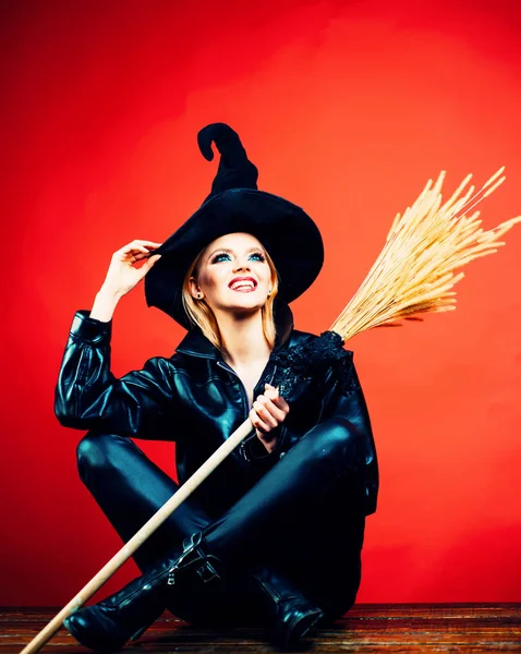 Feliz Dia das Bruxas. Jovens mulheres emocionais em trajes de Halloween em festa sobre fundo vermelho com abóbora. Bruxa segurando vassoura ou vassoura . — Fotografia de Stock