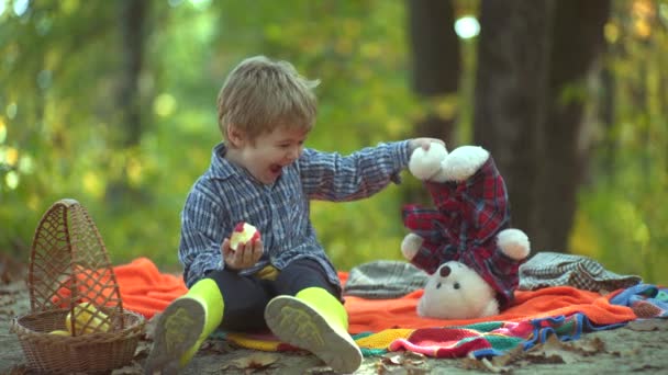 Niños lanzando hojas amarillas y rojas. Esperando en el parque de otoño. Niño de otoño. Niño pequeño y muy lindo en ropa vintage con maleta en el fondo de las hojas de otoño . — Vídeo de stock