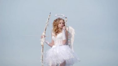 Işık lı bir arka plan üzerinde bir melek gibi giyinmiş Sevgililer Daygirl Kavramı. Bulut üzerinde Sevimli genç cupid - gökyüzü arka plan. Masum çocuk kavramı