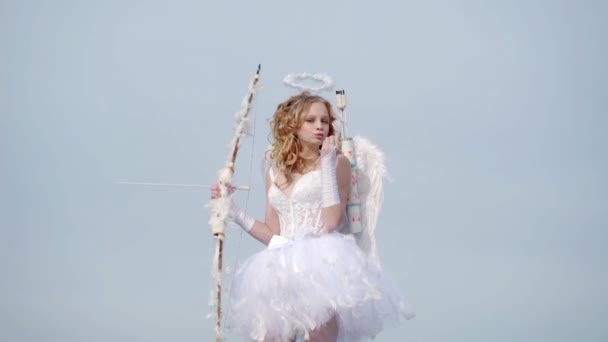 明るい背景に天使の格好をしたバレンタインデーガールのコンセプト。雲の上にかわいい十代のキューピッド - 空の背景。無邪気な子供の概念 — ストック動画