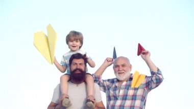 Çoklu nesil. Aile nesli: gelecek rüya ve insan kavramı. Mutlu dedesi baba ve torun mavi gökyüzü ve bulutlar arka plan üzerinde oyuncak kağıt uçak ile.