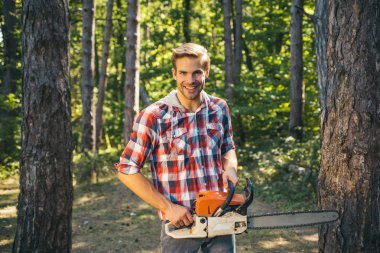 Erkek işi yapan adam. Mutlu Woodworkers oduncu. Orman arka plan üzerinde testere ile Lumberjack. Tarım ve ormancılık teması. Yaz ormanında baltalı veya testereli oduncu.