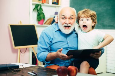 Büyükbabam torunuyla konuşuyor. Eğitim ve okuma kavramı. Baba ve oğul. Büyükbaba ve torunu birlikte öğreniyorlar. Öğrenme ve eğitim kavramı.