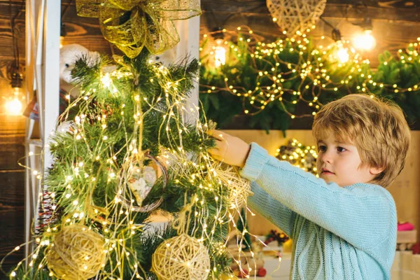 Dziecko dekorowanie choinki z Bauble. Dekoracje świąteczne. Portret Mikołaja dziecko z bawidełko patrząc na kamerę. Szczęśliwego nowego roku. — Zdjęcie stockowe