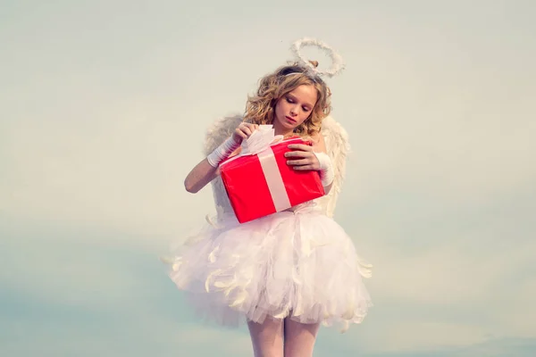 Valentines Day Card. Tiener Cupid Angel met geschenk. Engel kinderen meisje met witte vleugels. Concept van Valentines Daygirl gekleed als een engel op een lichte achtergrond. — Stockfoto