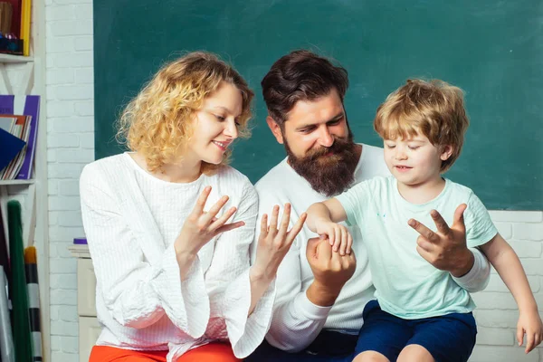 Young couple helping his son to make homework. Nice family photo of little boy and his Parents. Boy from elementary school. Counting on fingers. — Stock Photo, Image