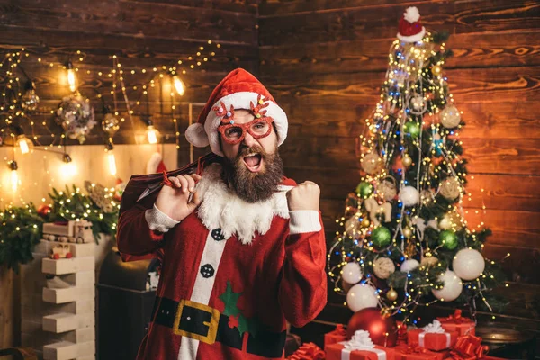 Happy Santa dressed in winter clothing think about Christmas near Christmas tree. Portrait of a brutal mature Santa Claus. — Stock Photo, Image