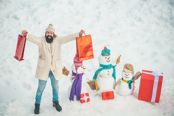 Guapo Santa Claus. Muñeco de nieve y hombre barbudo divertido en la nieve. El muñeco de nieve y el hombre divertido barbudo con el regalo - los amigos. Tarjeta de felicitación de Navidad . — Foto de Stock