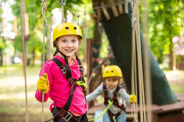 Little girl climbing on high rope park. Children fun. Helmet - safety equipment for Little girl playing. Little girl concept. Child. Climber child.