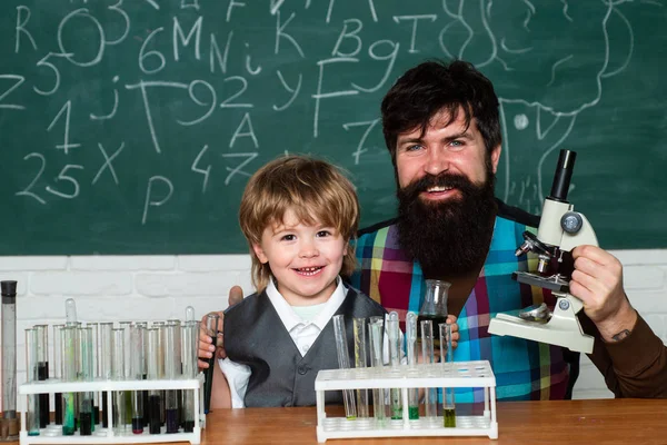 Elementary school teacher and student in classroom. Experiment. Teacher helping pupils studying at desks in classroom. Father and son. Home schooling. Wunderkind