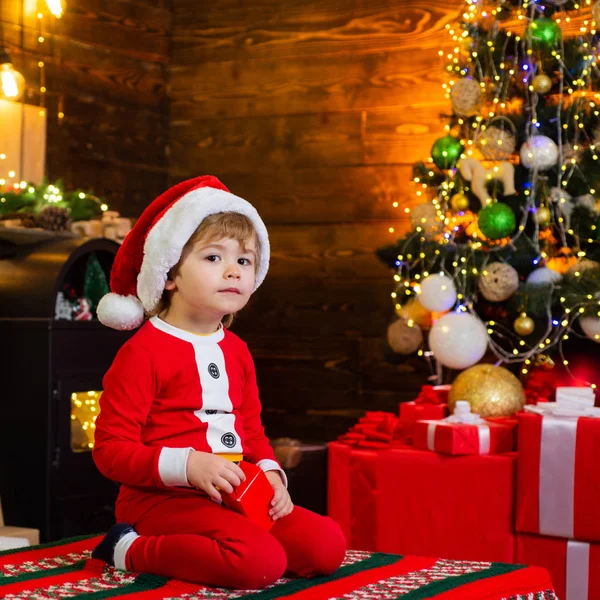 Mooie baby geniet van Kerstmis. Santa jongen kleine kind vieren kerst thuis. Jeugdherinneringen. Familie vakantie. Jongen schattig kind vrolijk humeur spelen in de buurt van kerstboom. Vrolijk en helder kerst — Stockfoto