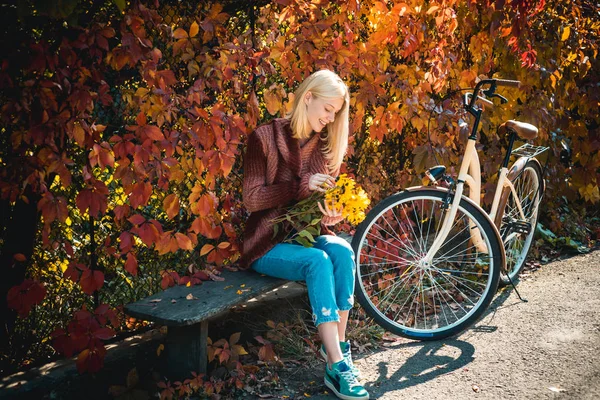 Menina sonhadora com cabelo loiro em camisola de malha. Bela jovem morena sentada em um outono caído deixa em um parque. Outono Vestuário e tendências de cor . — Fotografia de Stock