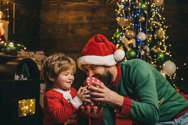 Yeni Yılınız Kutlu Olsun. Baba ve oğul internet kullanıyor. Küçük Noel Baba ve yaşlı sakallı Santa dizüstü bilgisayar kullanarak.