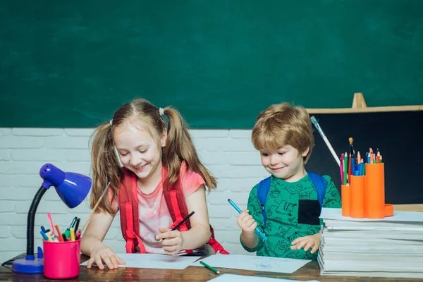 Torniamo a scuola. Ragazzo e ragazza delle elementari nel cortile della scuola. Bambino vicino alla lavagna in classe scolastica . — Foto Stock