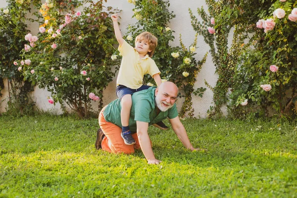 Bambino felice con il nonno che gioca all'aperto. Papa 'che da' un passaggio al figlio nel parco. Nonno con figlio e nipote si divertono nel parco . — Foto Stock
