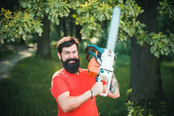 Lumberjack in the woods with chainsaw axe. Handsome young man with axe near forest.