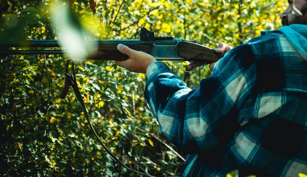 Κυνηγός με κυνηγετικό όπλο στο κυνήγι. Άνθρωπος κυνηγός με γένια που κρατάει όπλο και περπατάει στο δάσος. Κυνηγός με κυνηγετικό όπλο στο κυνήγι. — Φωτογραφία Αρχείου